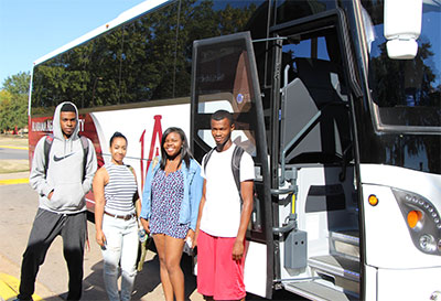 AAMU BTS bus with open doors. Four smiling students pose in front of the bus doors.