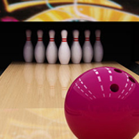 A pink bowling ball moves toward some bowling pins