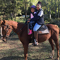 Mother and daughter ride a horse together