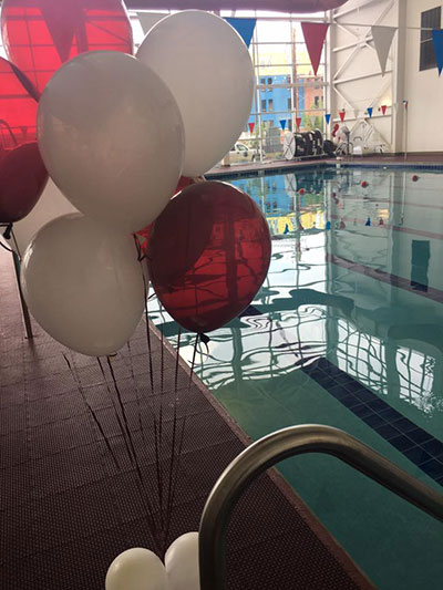 Photo of the Wellness Center's swimming pool with maroon and white balloons in the foreground